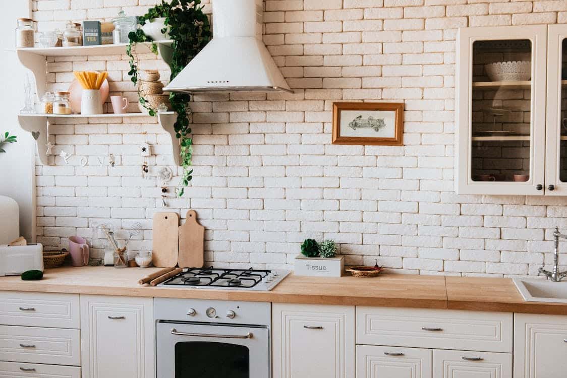 A modern looking kitchen with white brick background.