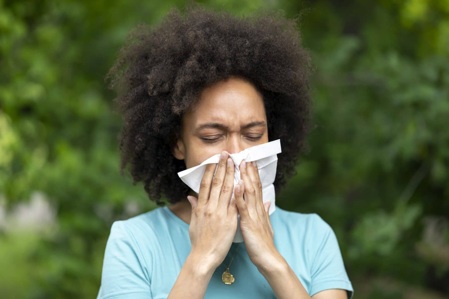 A woman with Sinusitis Problems is Feeling Displeased and Blowing Nose in Napkin During a Walk in City Park During a Summer Day.